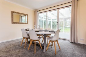 A dining area with a table set for four, surrounded by chairs with wooden legs. - Toast Stays - The Sunroom House (Durham)