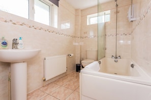 A bathroom with a bathtub, toilet, and sink. - Toast Stays - The Sunroom House (Durham)