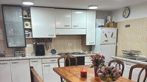 A kitchen with white cabinets, a wooden table, and a bench. - Discover the relaxation of the mountains in this detached villa surrounded by greenery. (Abruzzo)