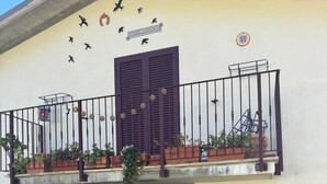 A building with a balcony, a door, and a stone-paved entrance. - Discover the relaxation of the mountains in this detached villa surrounded by greenery. (Abruzzo)