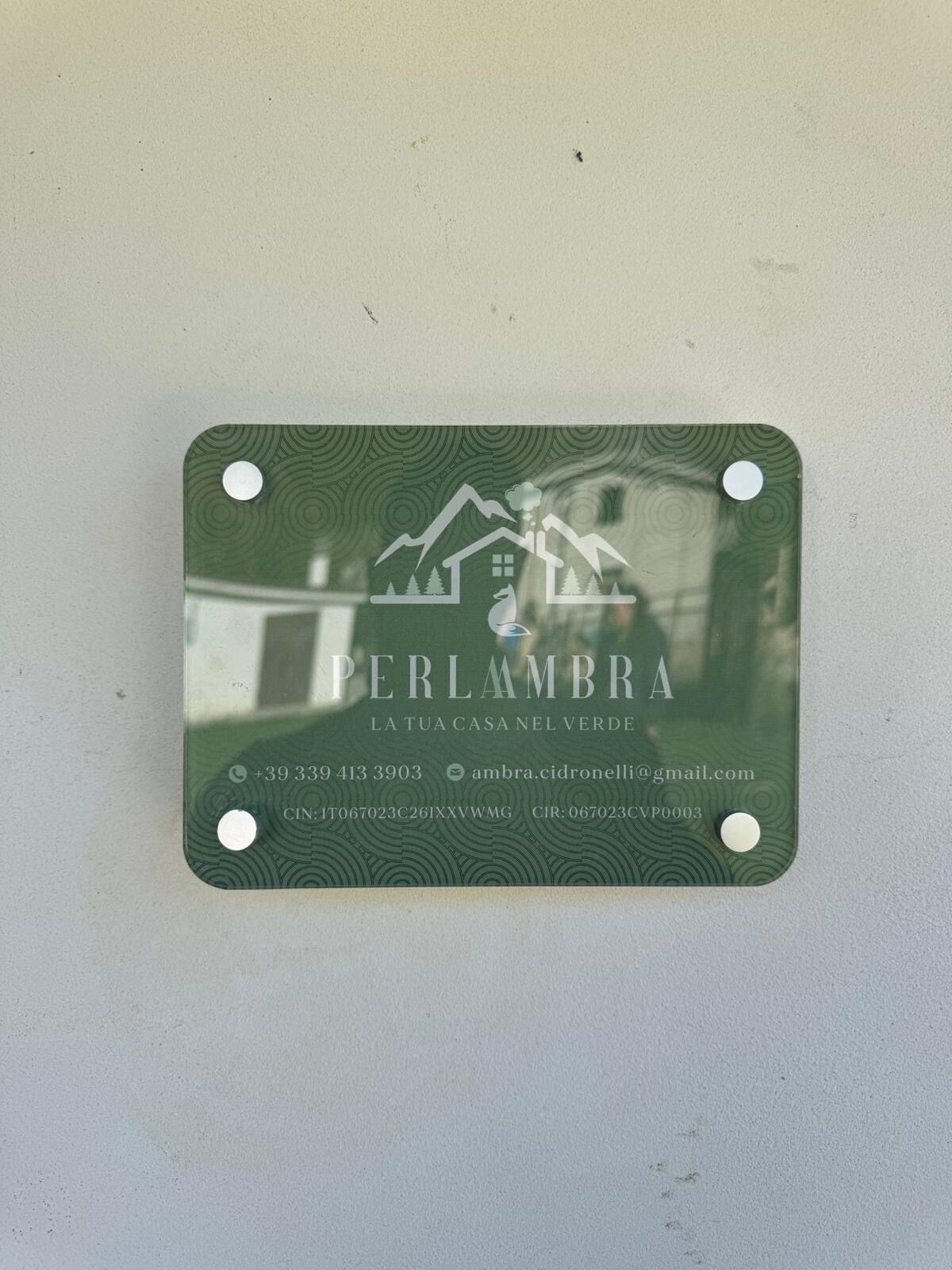 Een visitekaartje voor 'PERLAMBRA' met contactgegevens en een logo met een huis en bergen.