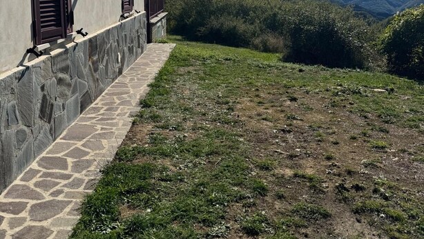 A building with stone steps and shutters, a stone wall, and a view of mountains. - Discover the relaxation of the mountains in this detached villa surrounded by greenery. (Abruzzo)