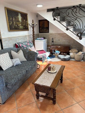 A living room with a sofa, a coffee table, a fireplace, a staircase, and a painting on the wall. - Discover the relaxation of the mountains in this detached villa surrounded by greenery. (Abruzzo)