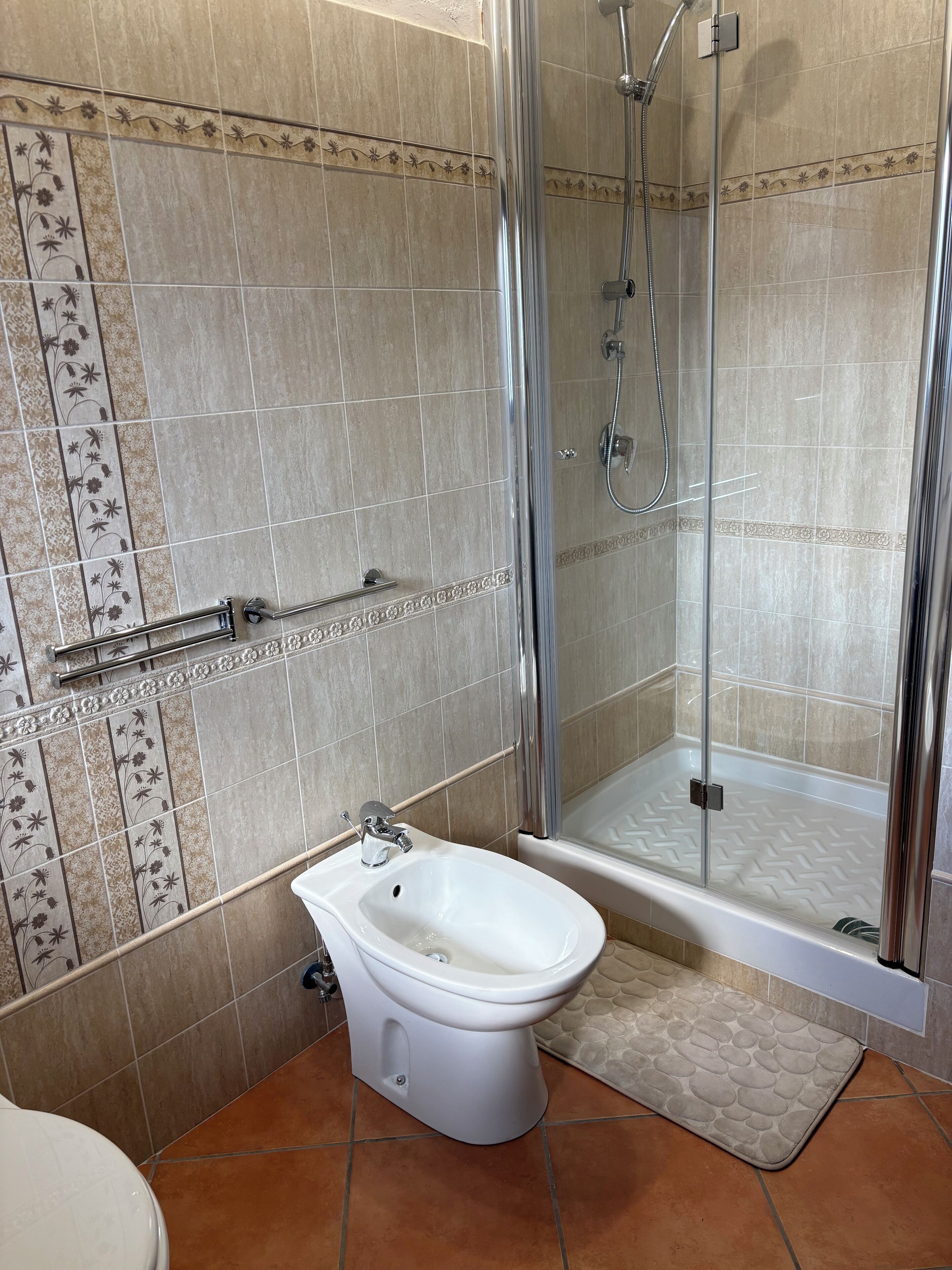 Une salle de bain avec douche, toilettes et bidet.