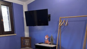A bedroom with a bed, a TV mounted on the wall, a wooden chair, and a small table with a fox decoration. - Discover the relaxation of the mountains in this detached villa surrounded by greenery. (Abruzzo)