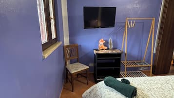 Une chambre à coucher avec un lit, une chaise, un bureau, une télévision et une fenêtre.