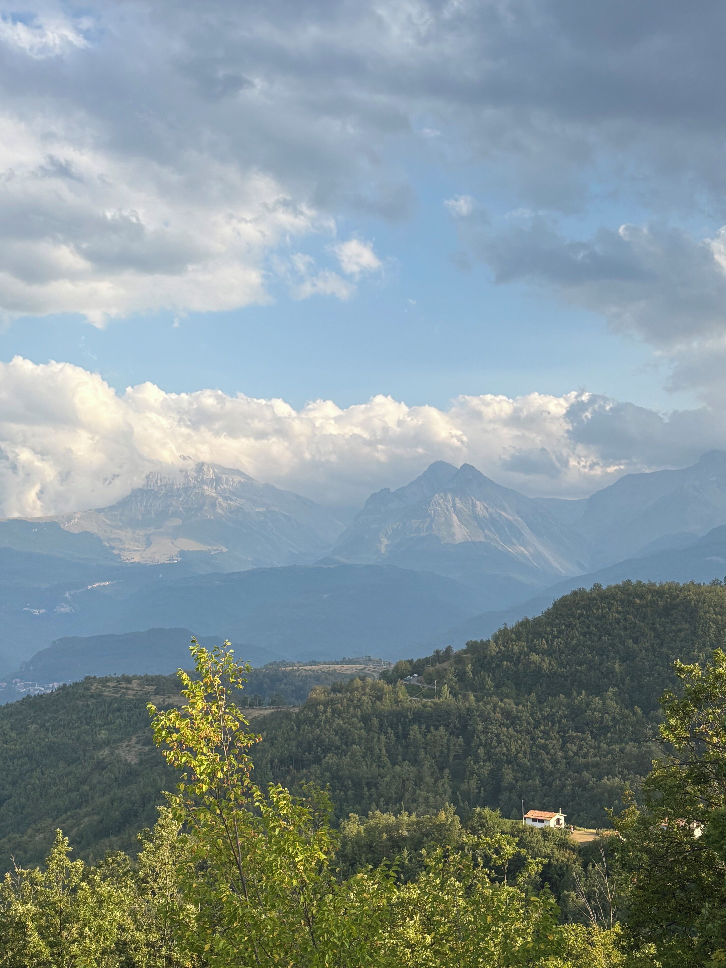 Eine Berglandschaft mit einem kleinen Gebäude auf einem Hügel.