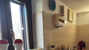 Una cocina con salpicadero de azulejos, armarios blancos y una ventana con vista a árboles.