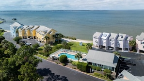 A coastal hotel with multiple buildings, a swimming pool, and a view of the sea.