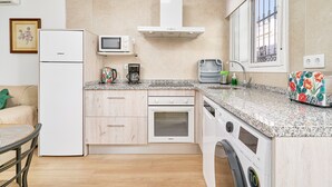 Une cuisine compacte équipée d’un réfrigérateur, d’un four à micro-ondes, d’un four et d’un lave-linge.