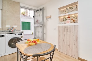 Une cuisine compacte équipée d’un lave-linge, d’une table à manger avec un set de table et d’un meuble en bois.