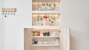 Une cuisine avec des étagères en bois, un luminaire suspendu et divers ustensiles de cuisine.