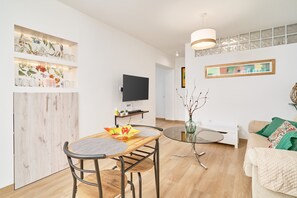 Ein modernes Wohnzimmer mit Essbereich, einem Flachbildfernseher und einer Wandverkleidung.