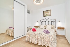 Une chambre à coucher comprenant un lit, des tables de chevet, un miroir et un tableau accroché au mur.