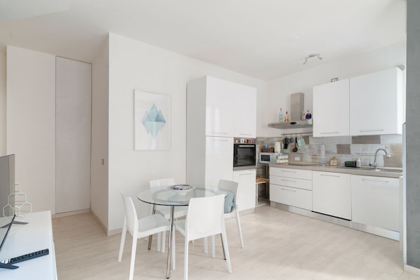 Une cuisine moderne avec des meubles blancs, une table à manger avec des chaises et un îlot de cuisine.