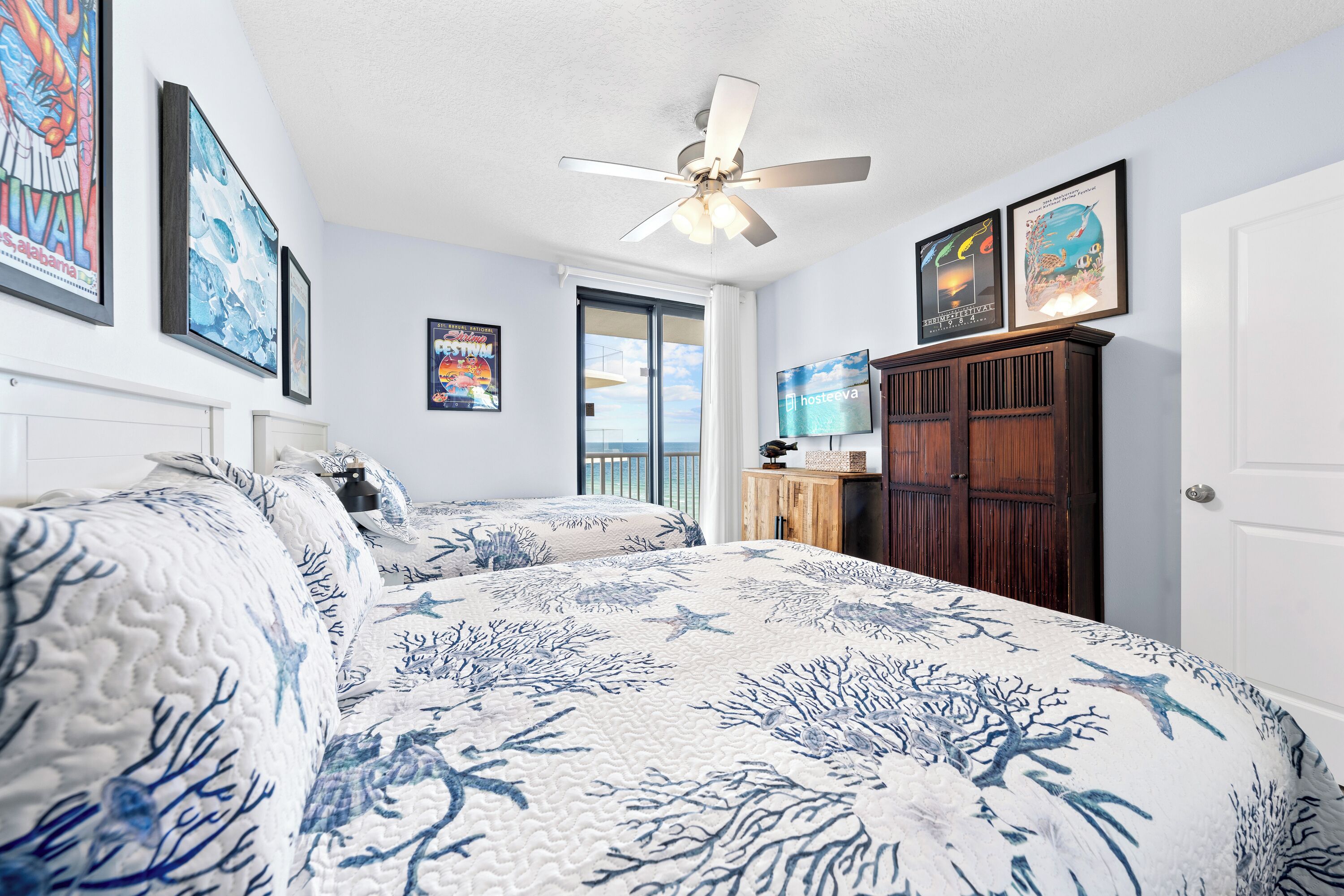 A bedroom with a bed, a ceiling fan, and a view of the ocean through a window.