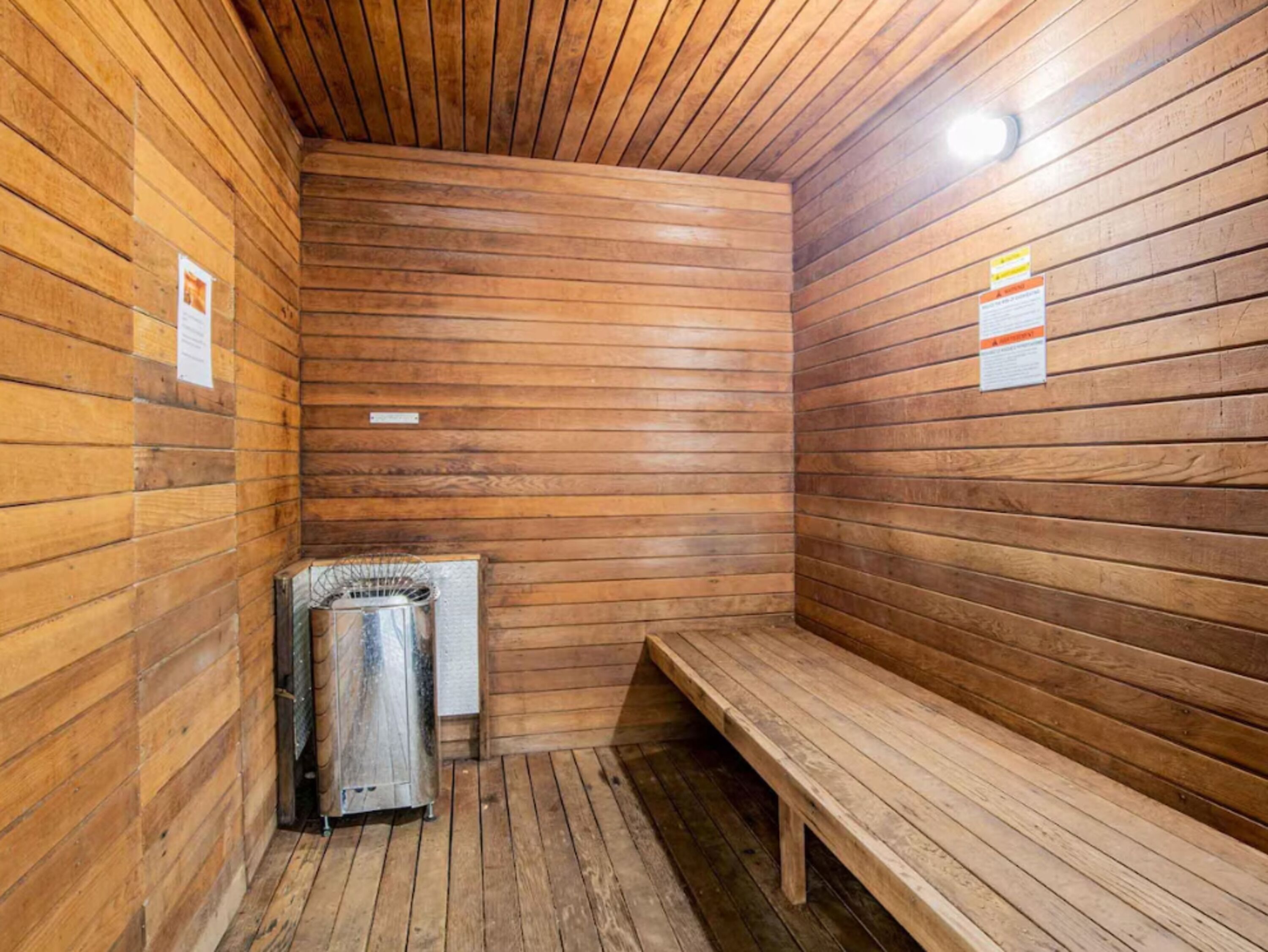 A sauna room with wooden walls and a bench.