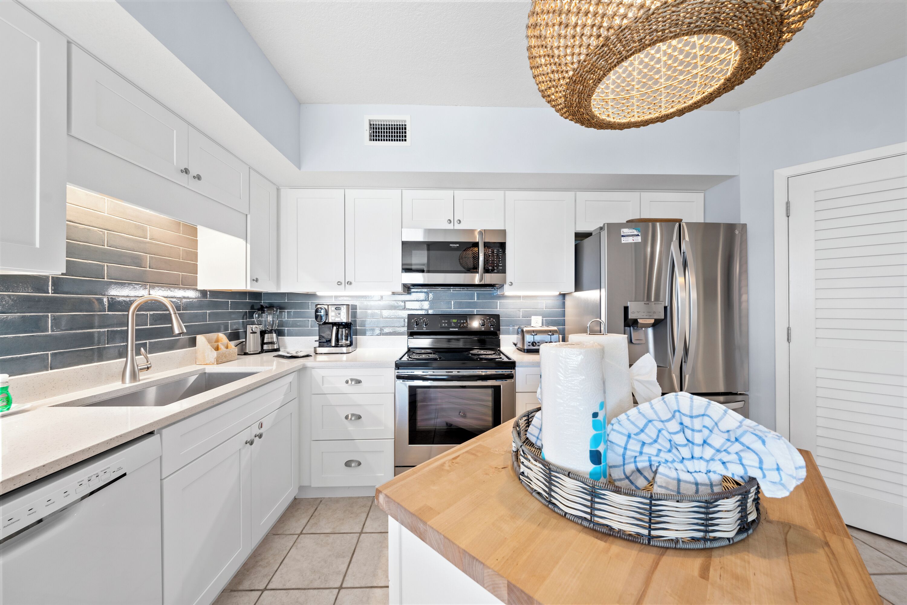 A modern kitchen with white cabinets, a stainless steel refrigerator, a microwave, and a stove.