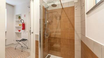 Un baño moderno con ducha de vidrio, extintor y barra para toallas.