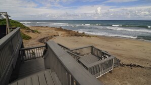 A wooden deck leading to a beach with ocean views. - Stuart Beach House- Ocean-to-river with stunning views, private dock & hot tub! (Stuart)