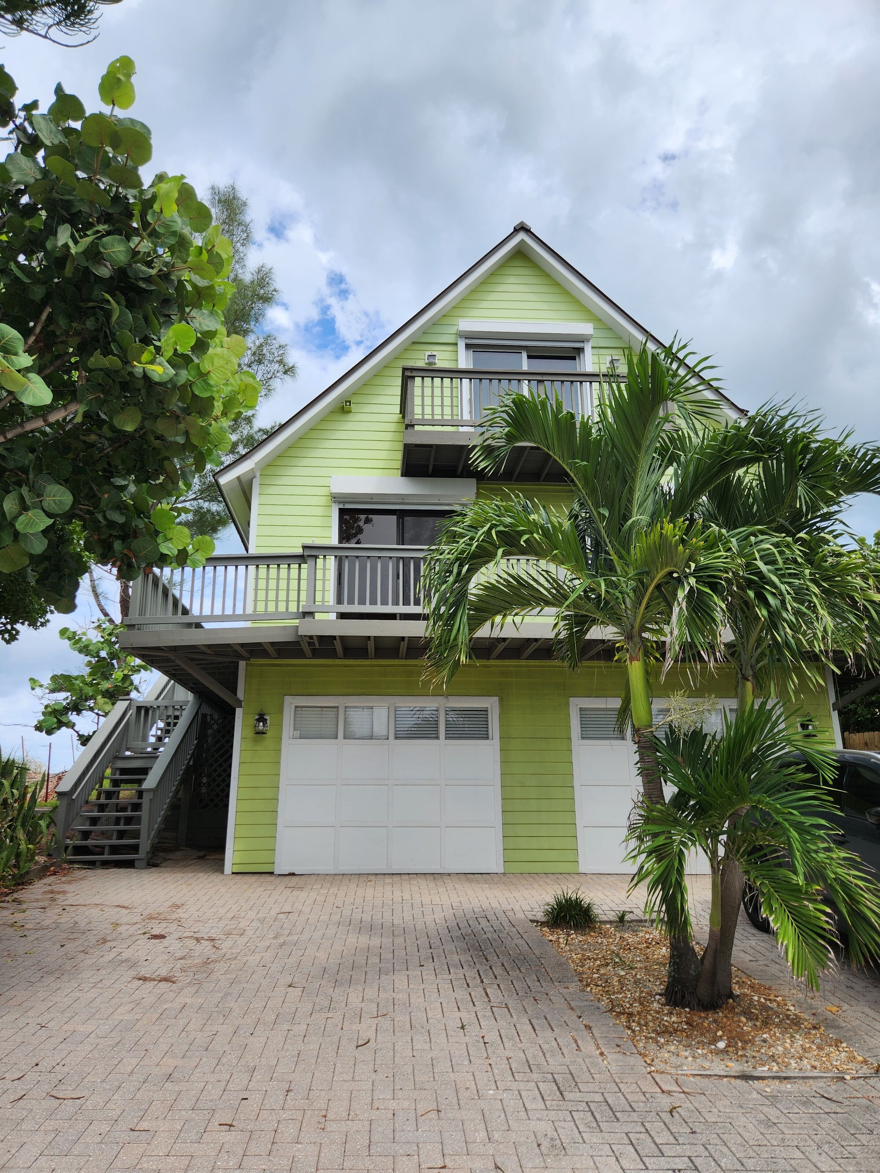 A two-story house with a green exterior, a front garage, and a staircase leading to the upper level.