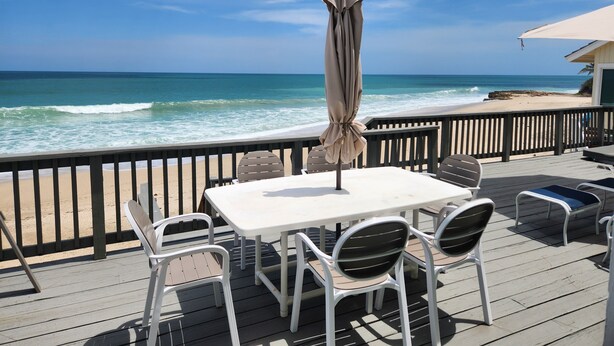 A deck with a table and chairs overlooking the ocean. - Stuart Beach House- Ocean-to-river with stunning views, private dock & hot tub! (Stuart)