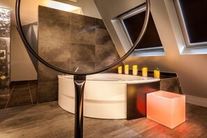 A modern bathroom with a round bathtub, a mirror, and a window. - Legend Hôtel Paris (Paris)