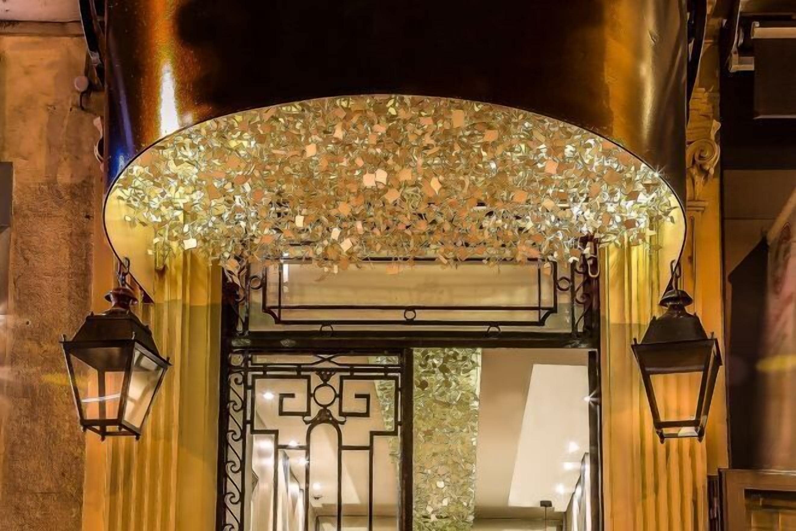 Entrada de un edificio con un toldo de cristal decorativo y una puerta de metal.