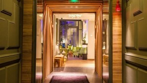Hall d'hotel dal design moderno, con reception, area relax e lampadario decorativo.