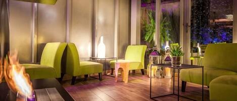 Ein stilvoller Lounge-Bereich mit grünen Sesseln, einem kleinen Tisch und einem Kamin.