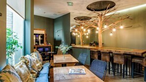 Un ristorante accogliente con tavoli e sedie in legno, un'area bar e un'originale lampada a forma di albero.