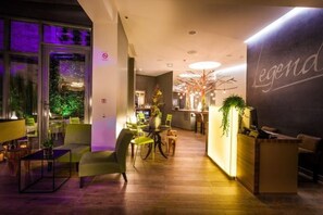 A hotel lobby with a reception desk, seating area, and a large window. - Legend Hôtel Paris (Paris)