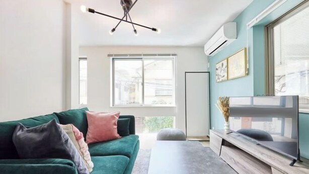Una sala de estar moderna con un sofá verde, una mesa de centro y un televisor sobre un mueble de madera.