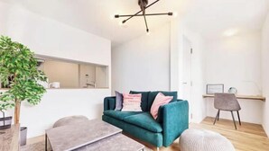 Una sala de estar moderna con un sofá color turquesa, una mesa de centro de madera, un reposapiés redondo y un diseño minimalista.