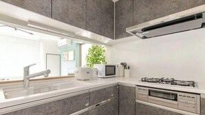 Una cocina moderna con gabinetes grises, encimera blanca, microondas integrado, cocina a gas y lavavajillas.