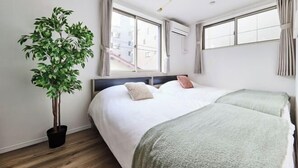 Un dormitorio con cama, planta en maceta y ventana.