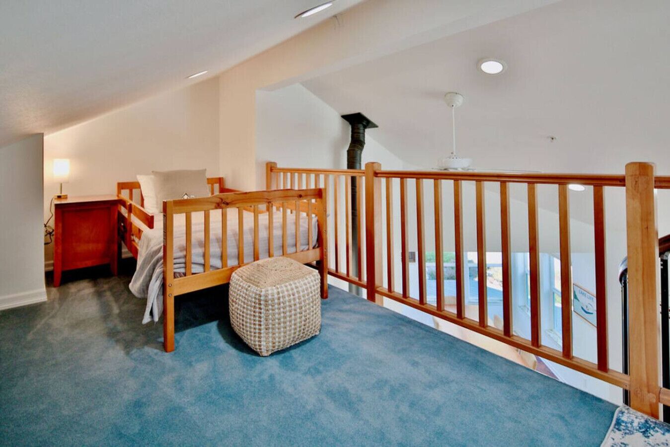 A bedroom with a wooden bed, a small bedside table, a red nightstand, and a blue carpet.