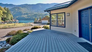 A house with a wooden deck, a blue door, and a view of mountains and a lake. - Cornerstone Haven – A Family Lakeside Escape (Port Angeles)