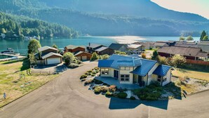 A residential area with houses, a driveway, and a lake with mountains in the background. - Cornerstone Haven – A Family Lakeside Escape (Port Angeles)