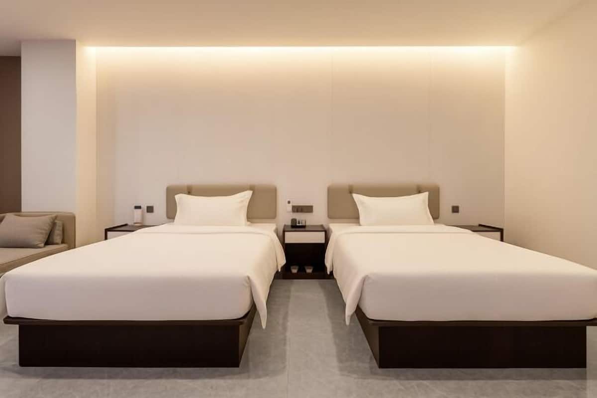 Une chambre d’hôtel avec deux lits, une table de chevet et une petite table.