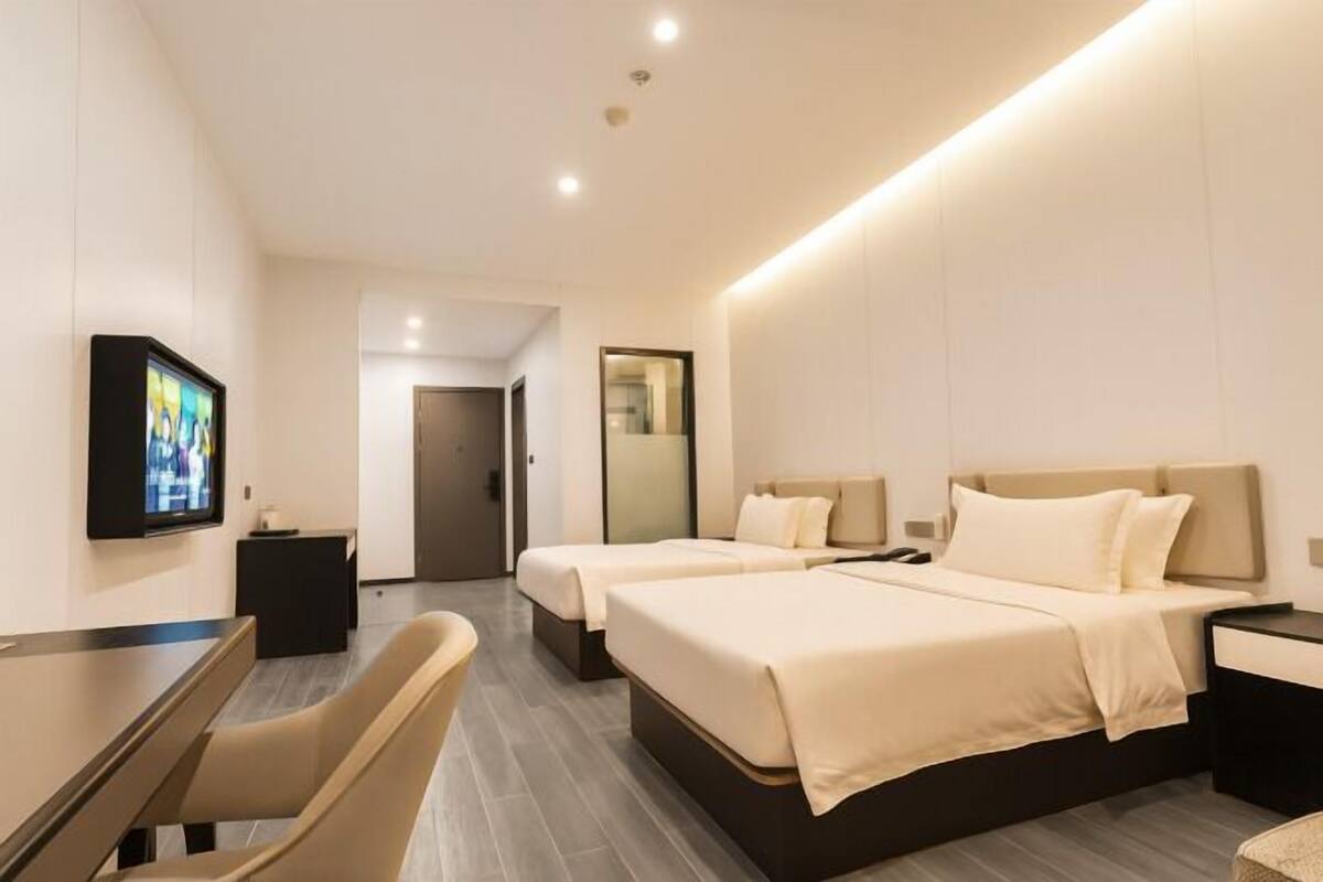 Une chambre d’hôtel moderne équipée de deux lits, d’une télévision, d’un bureau et d’une chaise.