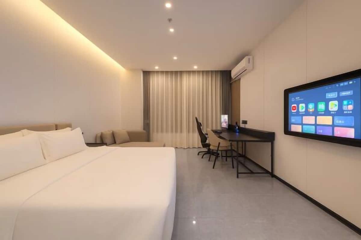 Une chambre d’hôtel moderne, dotée d’un grand lit, d’un bureau et d’un téléviseur à écran plat fixé au mur.
