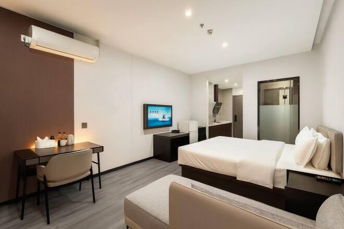 Une chambre d’hôtel moderne équipée d’un lit, d’un bureau, d’une chaise et d’un téléviseur.