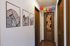 Un couloir orné de trois œuvres d’art encadrées, une porte décorée d’un motif ornemental et des ballons aux couleurs vives.