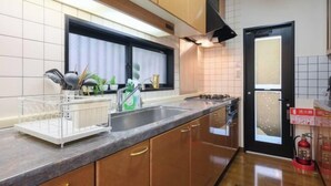 Eine moderne Küche mit Holzausstattung, einer Edelstahl-Spüle und einem Fenster mit Vorhängen.