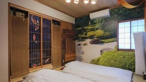 Ein Zimmer mit Tatami-Boden, einem Bett mit weißer Bettdecke, einer Schiebetür mit Blick auf Koi-Karpfen und einem Wandgemälde mit Gartenszene.