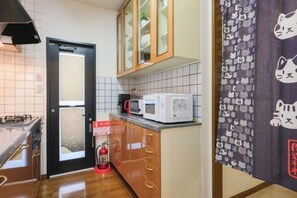 A kitchen with a microwave, cabinets, and a fire extinguisher.