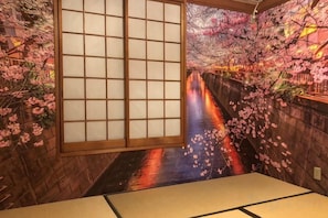 A traditional Japanese room with tatami flooring, a sliding shoji screen, and cherry blossom decorations. - Comfort Hasunuma (Tokyo)