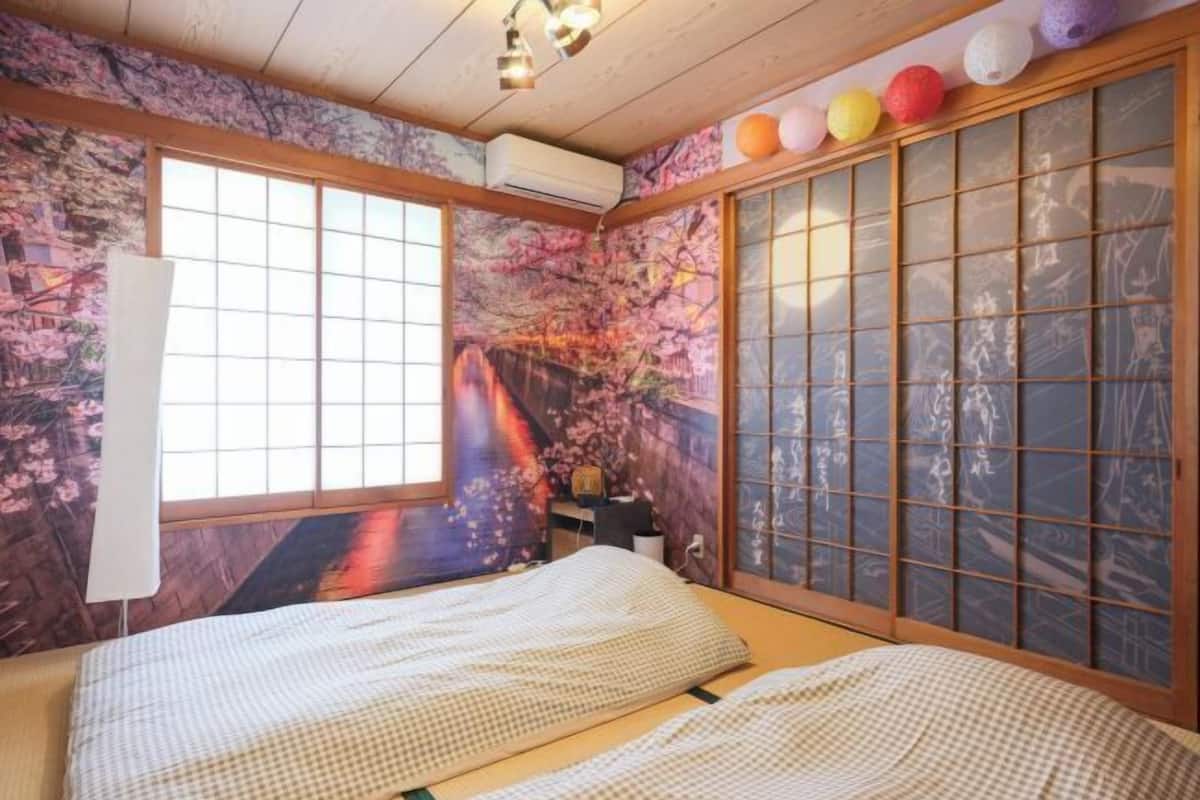 Une pièce de style japonais traditionnel, avec un sol recouvert de tatamis, un paravent shoji et une fresque représentant des fleurs de cerisier.