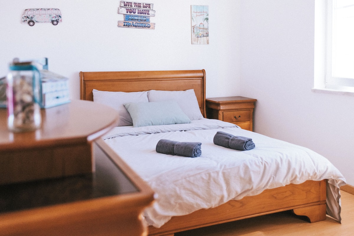 A neatly made bed with a wooden headboard, a bedside table, and a nightstand.
